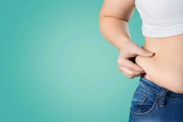 Image of woman pinching her love handles to show weight gain Ilkeston